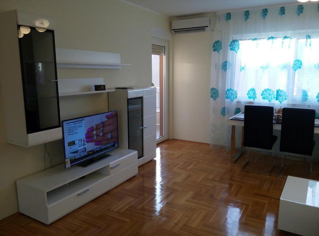 ein Wohnzimmer mit einem TV und einem Tisch mit Stühlen in der Unterkunft Apartman in Budva Podkošljun in Budva