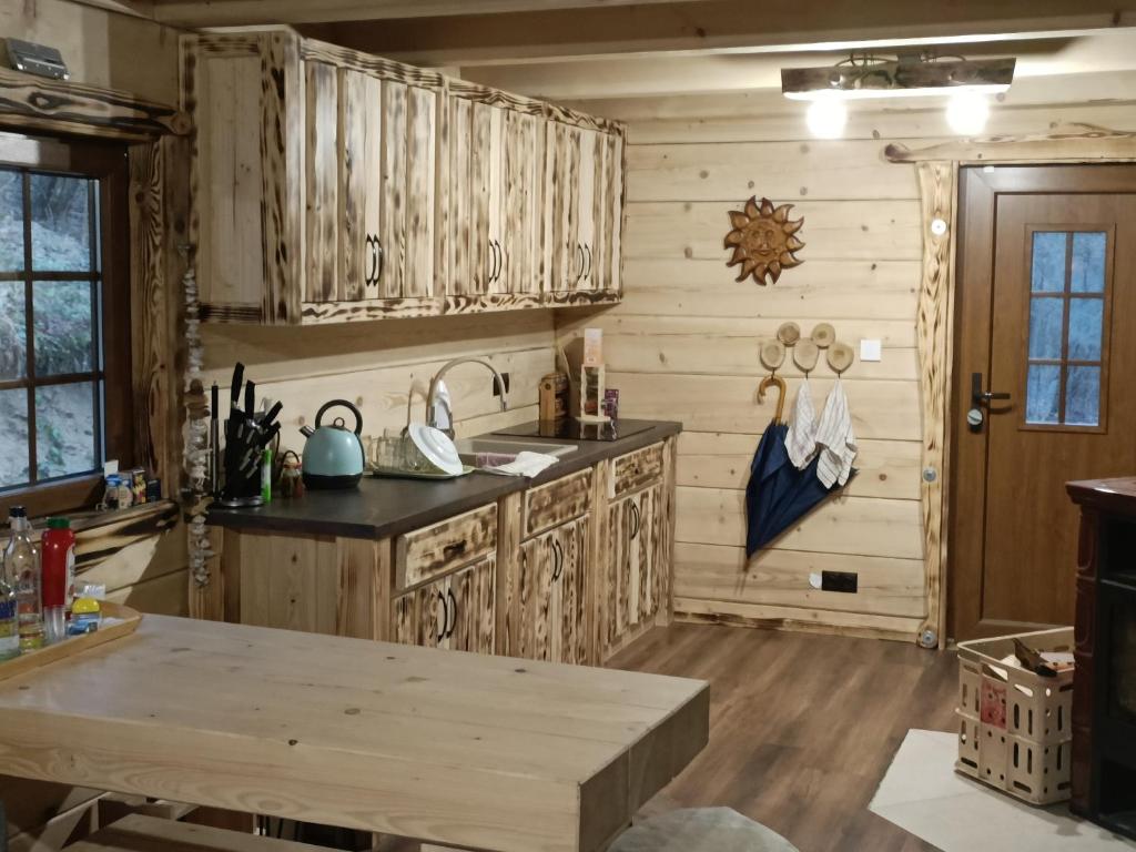 eine Küche mit Holzschränken und einem Tisch in der Unterkunft Chata Peťo in Bžany