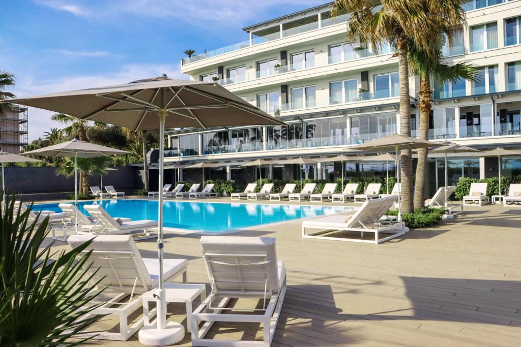 uma piscina com cadeiras e guarda-sóis e um hotel em Hotel & Resort Tre Fontane Luxury em Portici