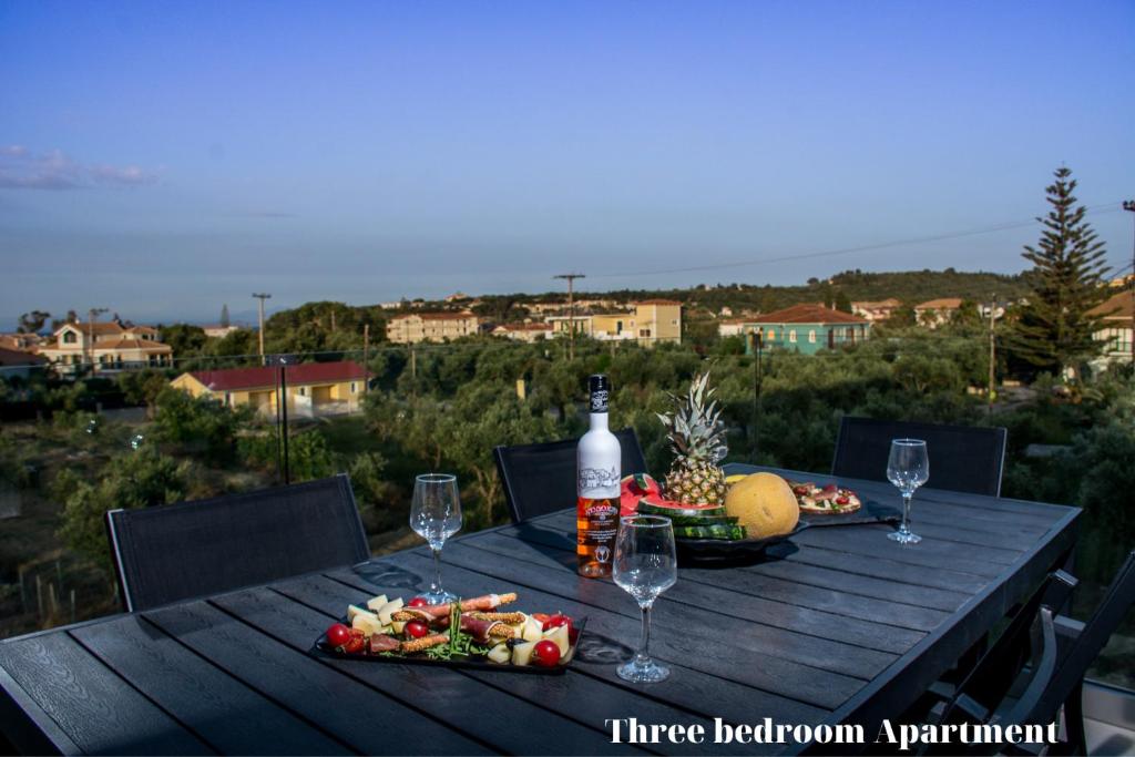 a wooden table with a bottle of wine and food at Dionisos Luxury Suites in Tsilivi