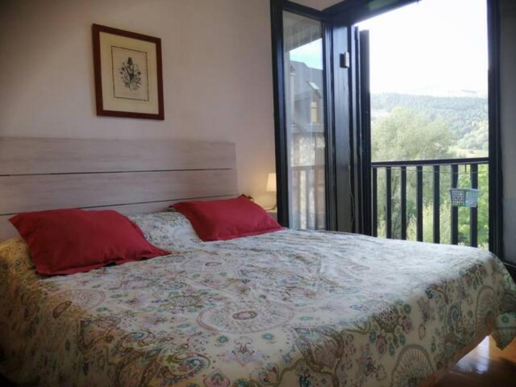 a bedroom with a bed with red pillows and a balcony at Apartamento con jardín y luminoso Besiberri 6 in Pla de l'Ermita
