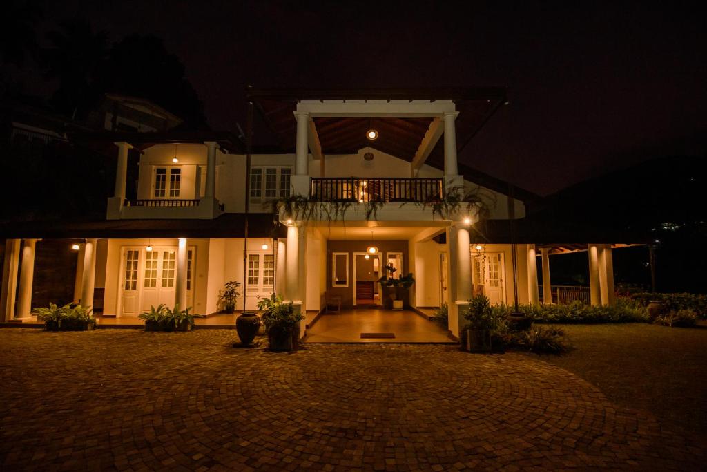 a large white house with a balcony at night at Kingsman House in Kandy