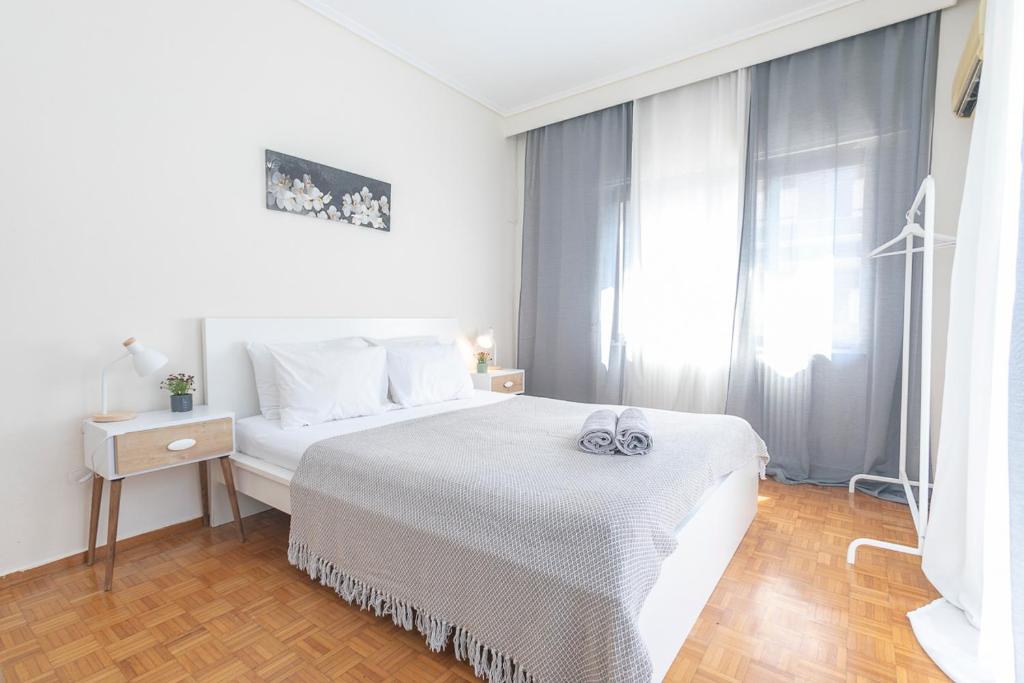 a white bedroom with a bed and a window at Houseloft Ambiance Park in Thessaloniki