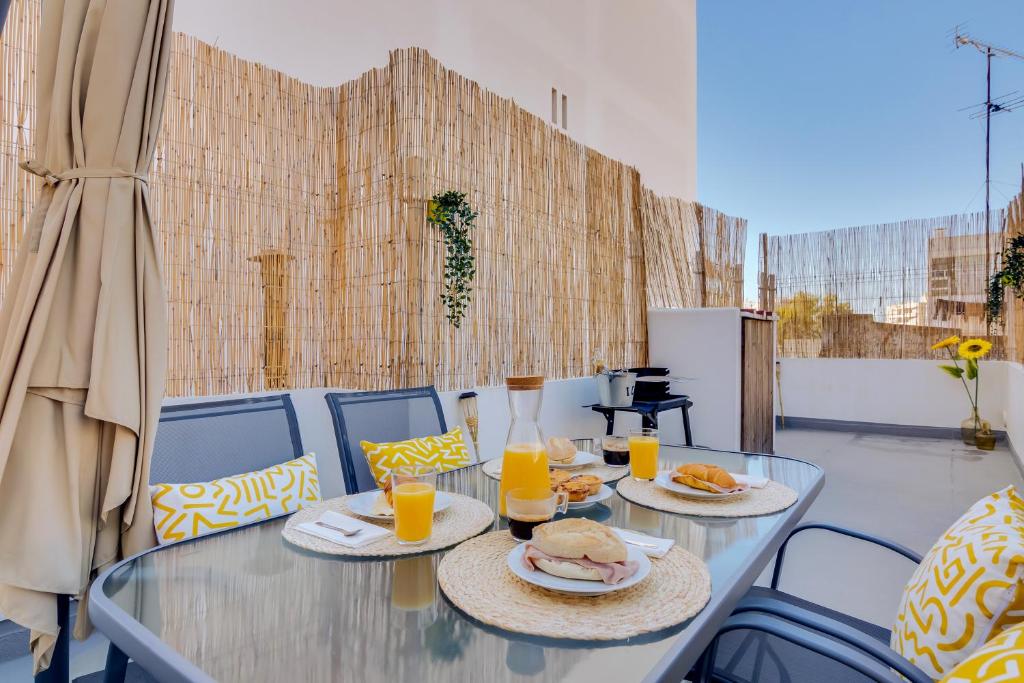 uma mesa de vidro com dois pratos de comida e sumo de laranja em Faro: Casa Trevo com terraço BBQ em Faro