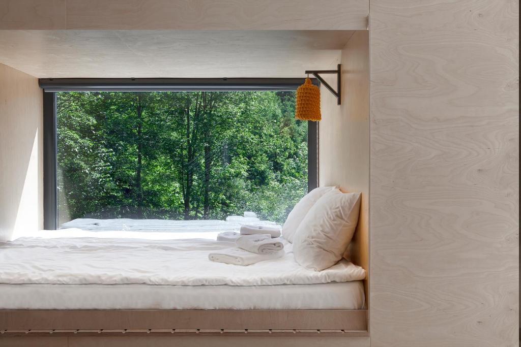 Cozy built-in bed facing large window overlooking green forest, folded towels and soft pillows.