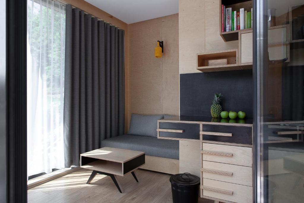 Small living nook with gray sofa, low coffee table, drawers, decorative pineapple and apples.