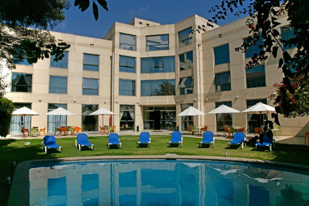 a hotel with chairs and a pool in front of a building at Hotel Costa Real in La Serena