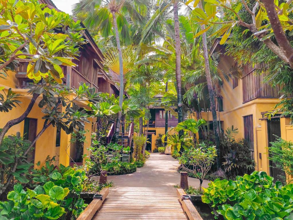 a walkway through the courtyard of a resort with palm trees at Buri Rasa Village Samui in Chaweng