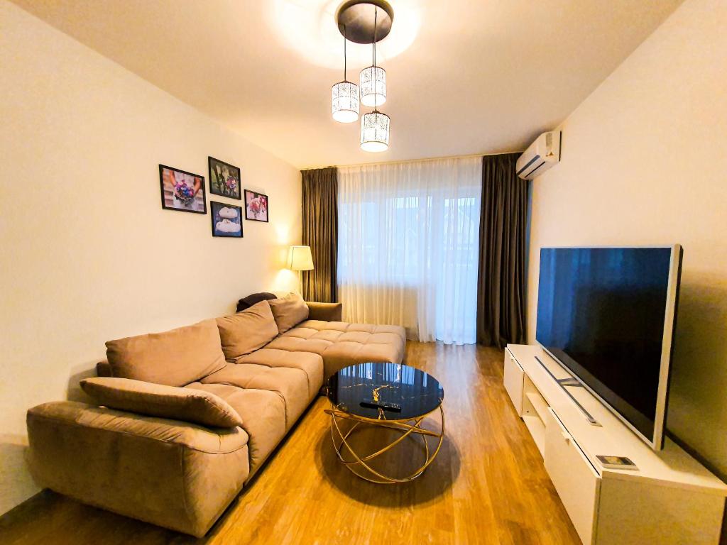 uma sala de estar com um sofá e uma televisão de ecrã plano em Luxurious Retreat 1BR Apartment with Netflix, Private Parking and self check in em Popeşti-Leordeni