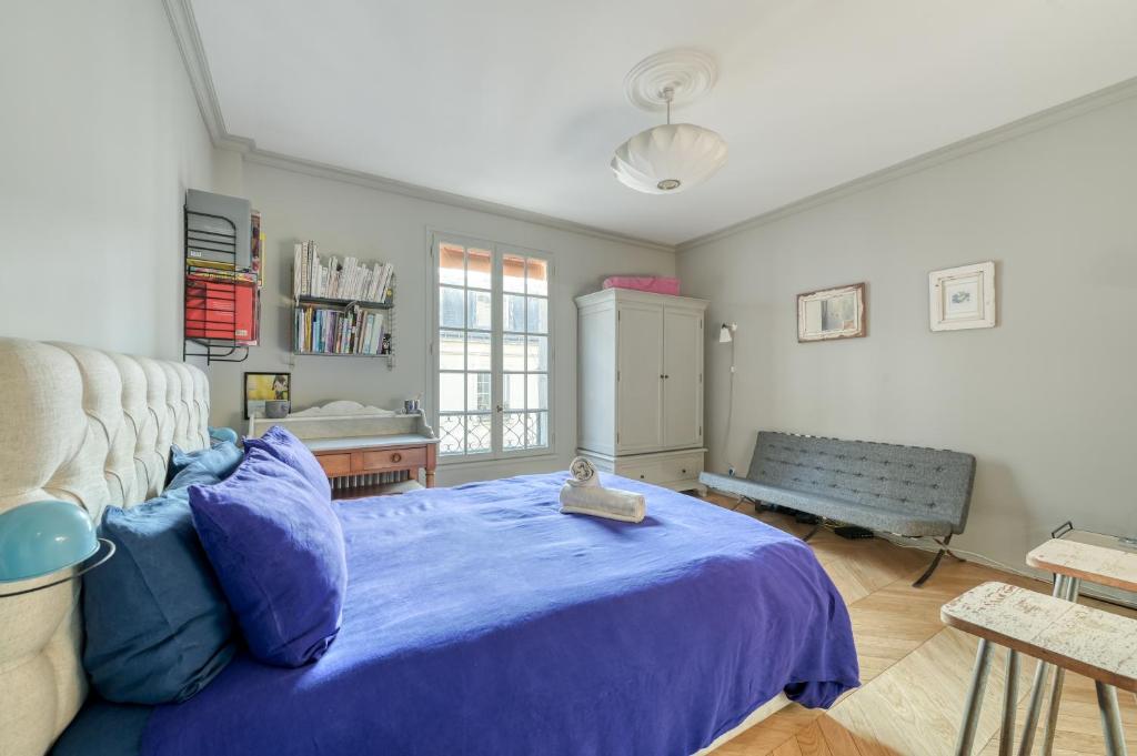 a bedroom with a blue bed and a bench at Perfect Parisian Apartment LeMarais for you! in Paris