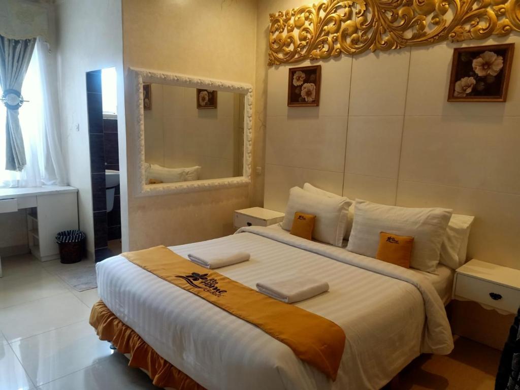 una camera da letto con un grande letto bianco e uno specchio di MY HOME @BALI HOTEL BY CONARY a Kuta