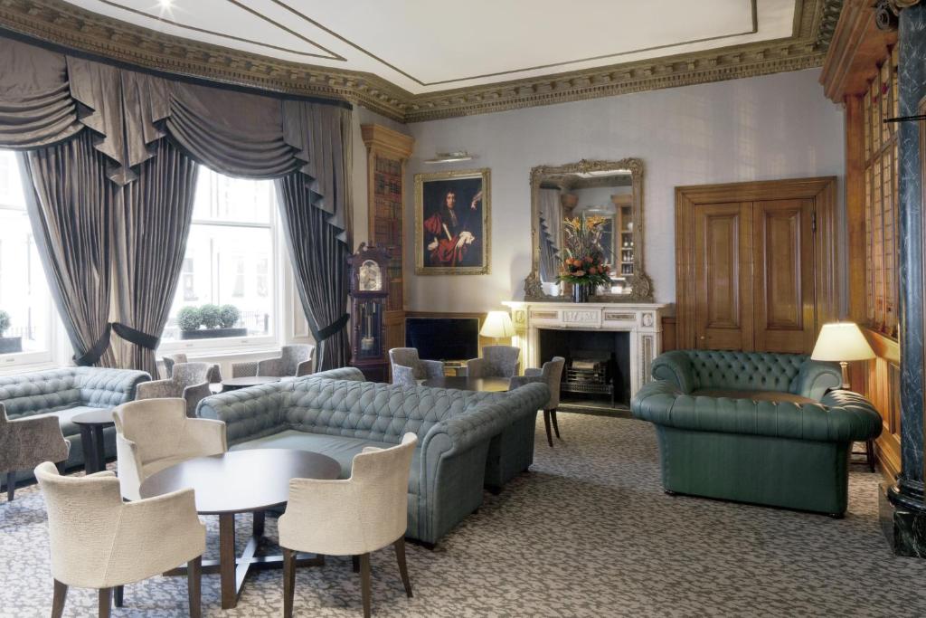 een woonkamer met banken en tafels en een open haard bij Gem Strathmore Hotel in Londen