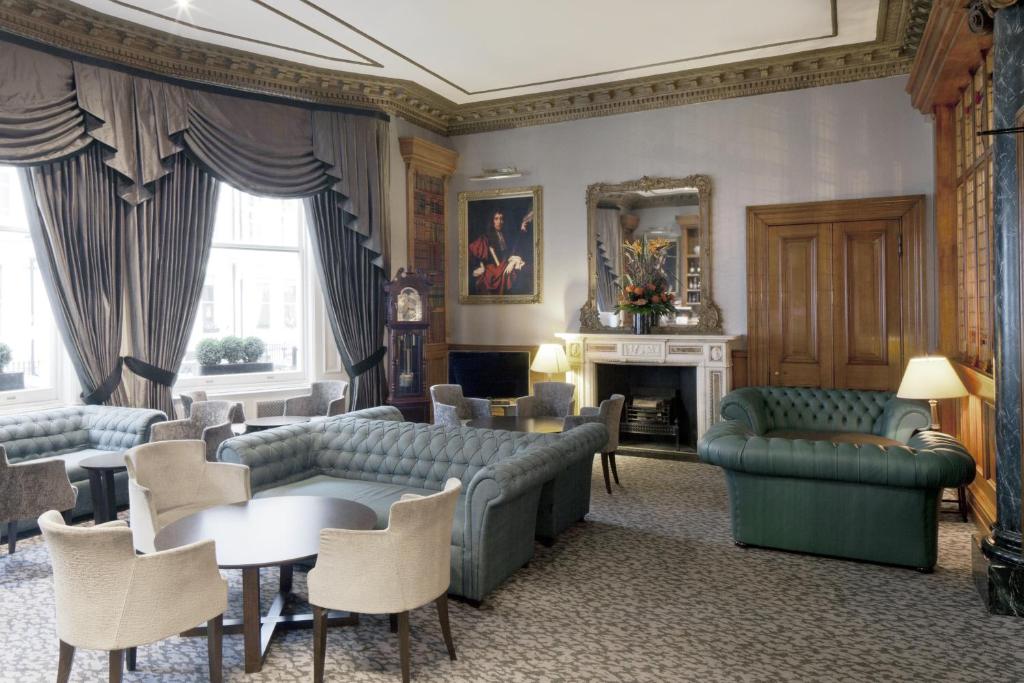 a living room with couches and tables and a fireplace at Gem Strathmore Hotel in London