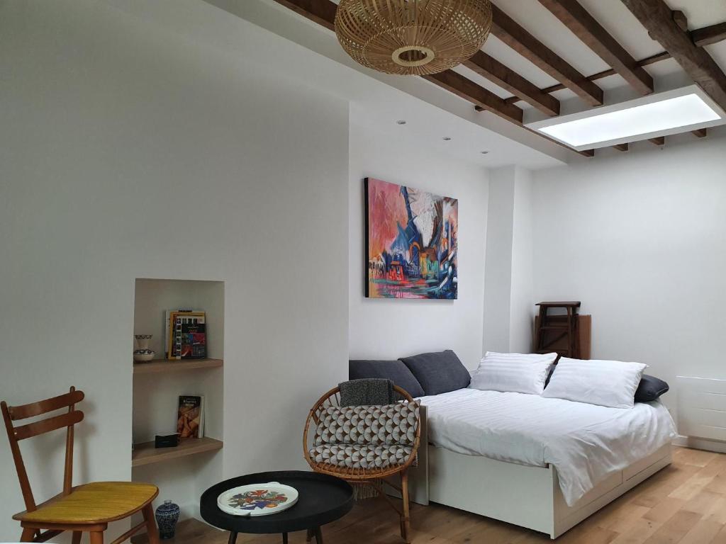 1 dormitorio con 1 cama, mesa y sillas en Chambre d'hôtes confort et charme Paris 9eme en París