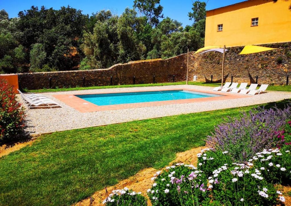 a swimming pool in a yard with chairs and flowers at Rural Mas Hortus in Girona