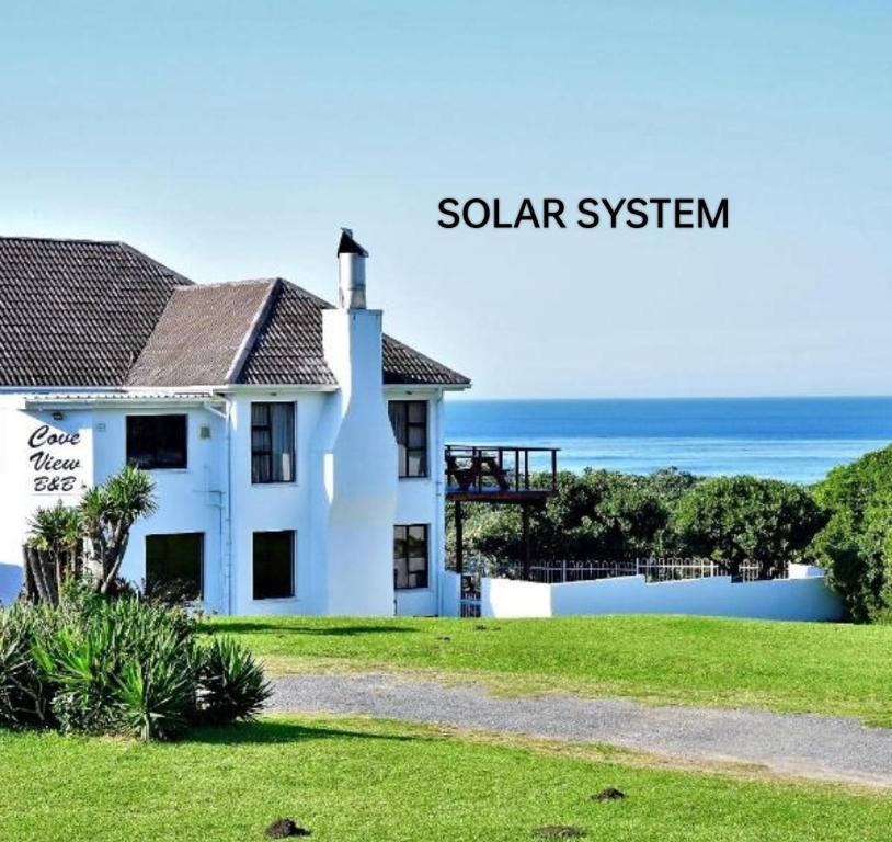 a white house with the ocean in the background at Cove View B&B in East London