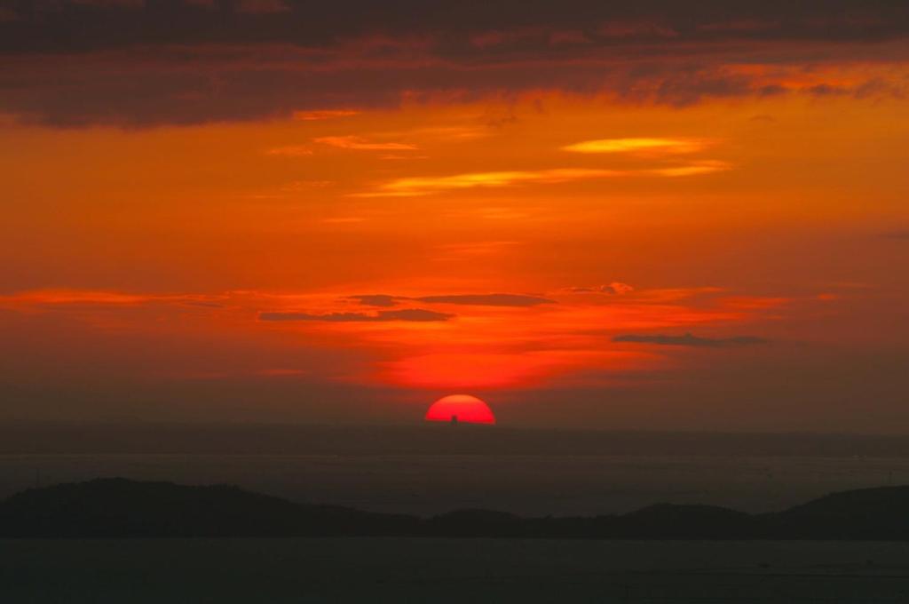 an orange sunset with the sun in the sky at Windfarm Nature Escape in Pililla