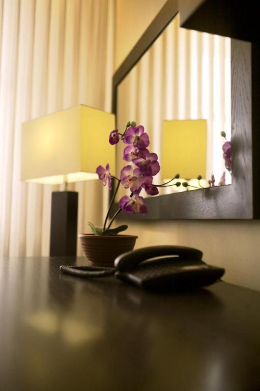 a table with a phone and a flower on it at Hotel Astory Plzeň in Plzeň