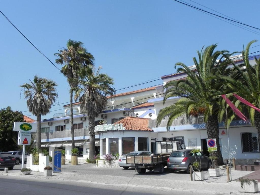 a building with palm trees in front of a street at Residencial Lareira do Pinheirinho in Almada