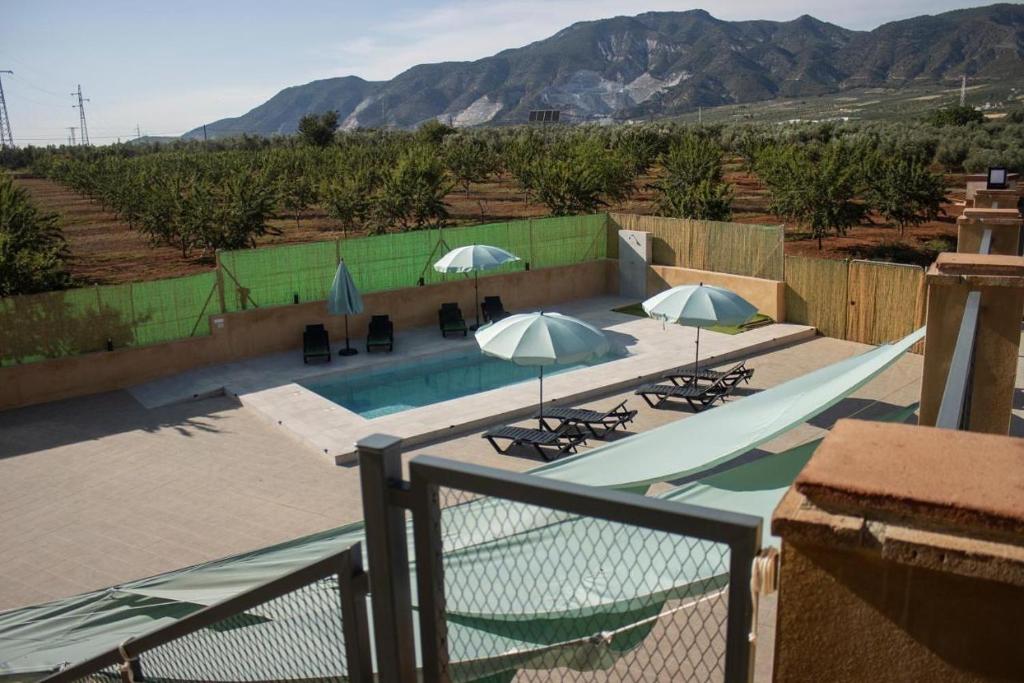 a pool with chairs and umbrellas on a balcony at Casa Rural Eralta in Dúrcal