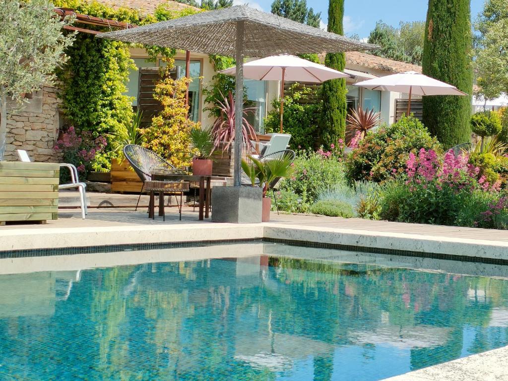 a swimming pool with a table and an umbrella at Villa Cabrida in Cabrières-dʼAvignon