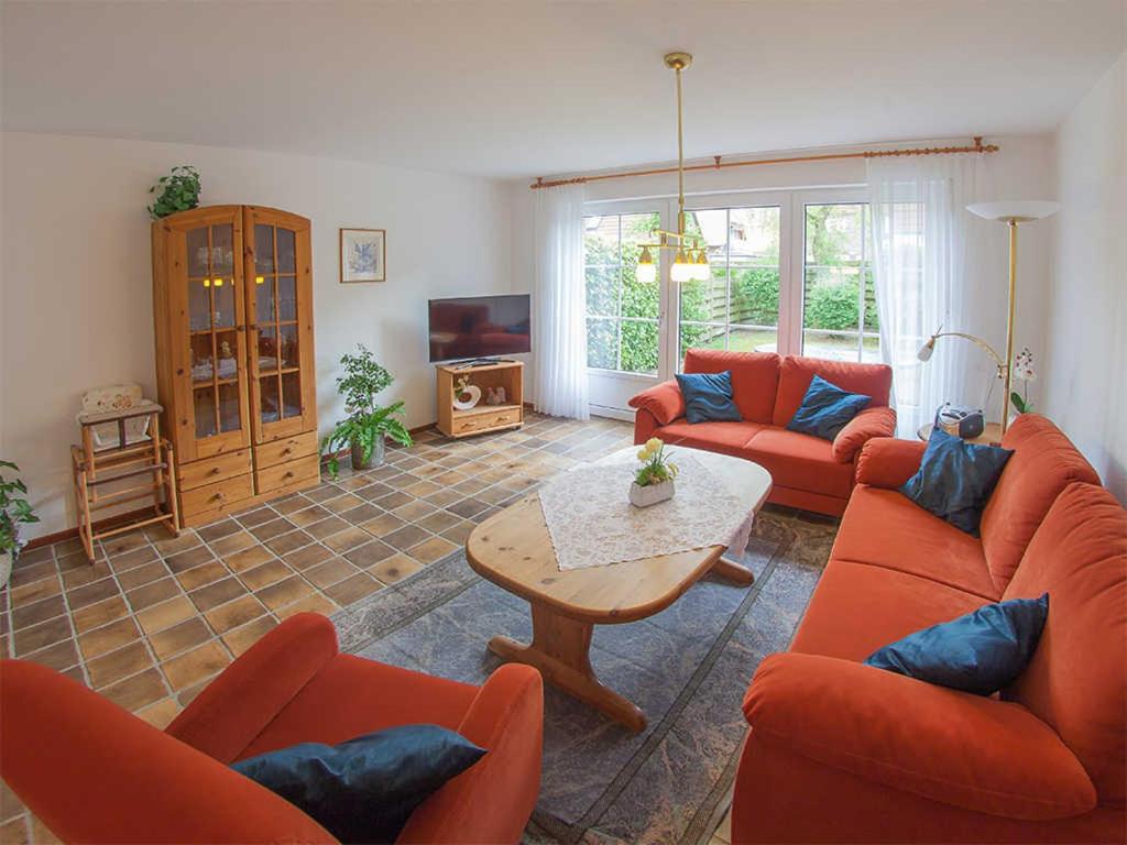 sala de estar con sofás naranjas y mesa en Ferienhaus Coyle, FeWo Vermittlung Nordsee, en Dangast