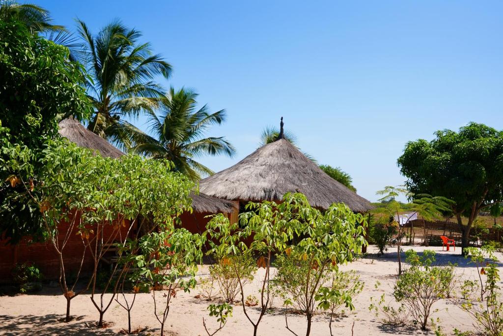 a couple of huts on a beach with trees at Campement Kaymba Lodge in Kachiouane