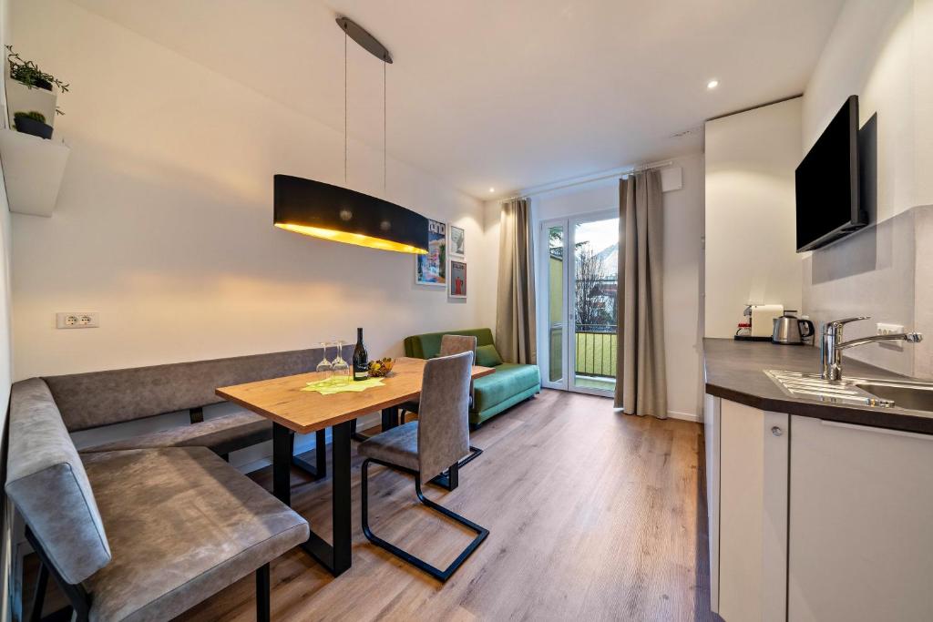 a kitchen and living room with a wooden table and chairs at Central Suite Meran in Merano