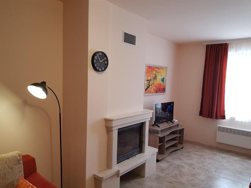 sala de estar con chimenea y reloj en la pared en Панорама Стойките Релакс, en Stoykite