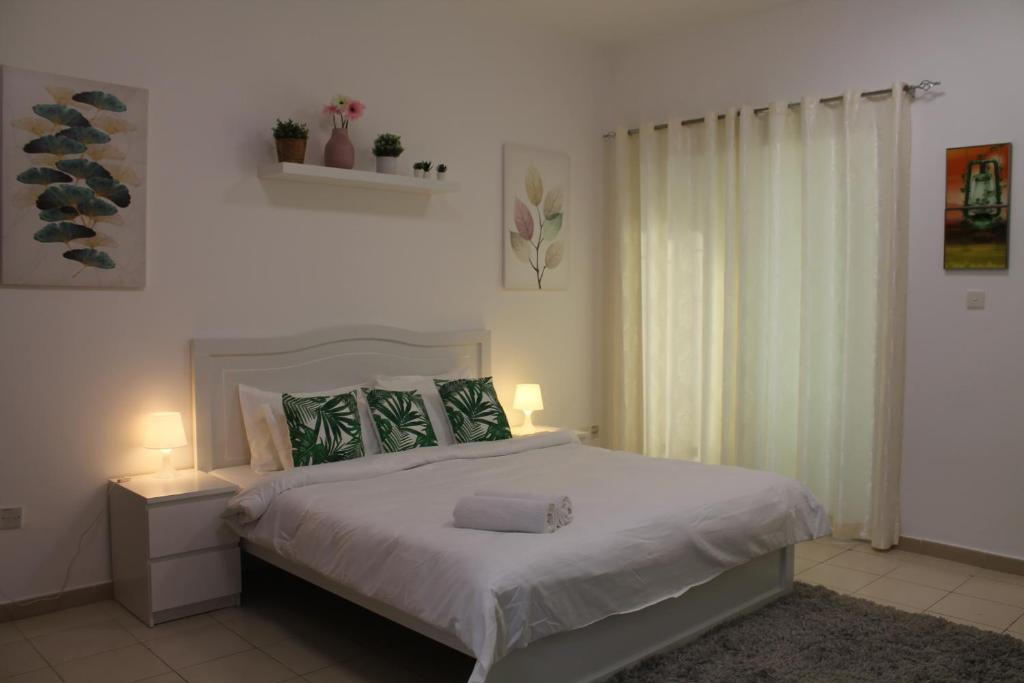 um quarto com uma cama grande e lençóis brancos em Bright, spacious and cozy studio apartment em Dubai