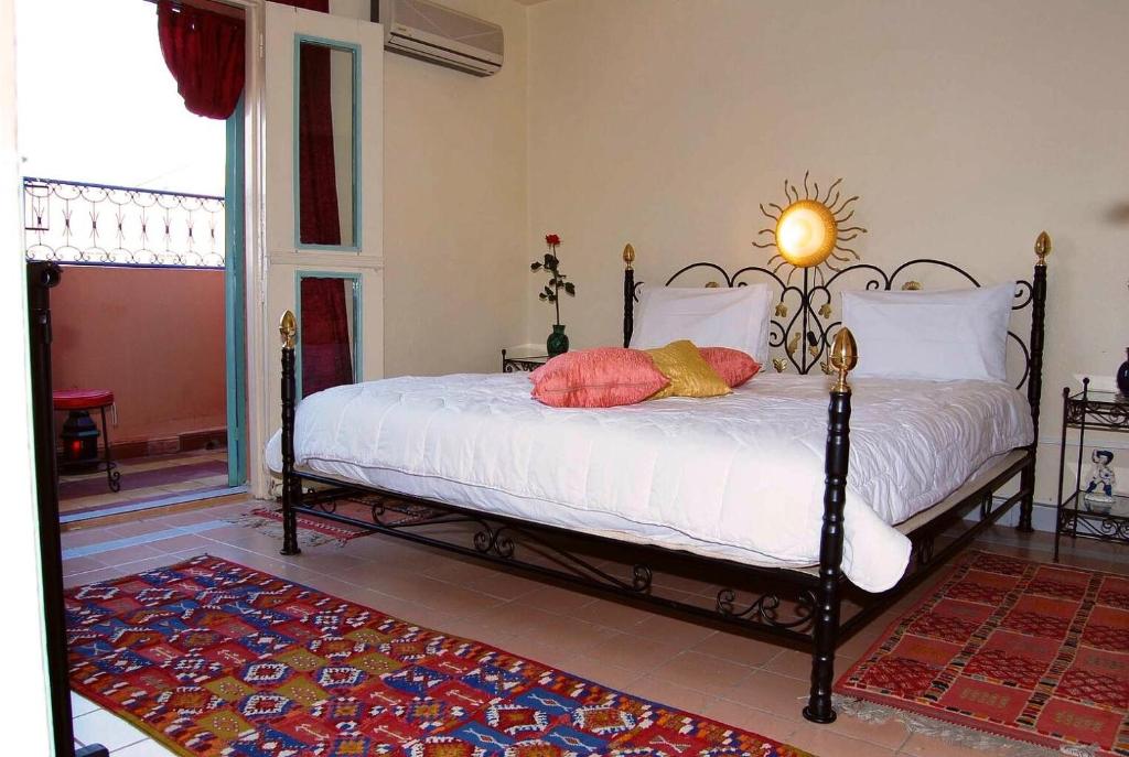 Schlafzimmer mit einem Bett mit weißer Bettwäsche und roten Kissen in der Unterkunft Chez Peyo in Marrakesch
