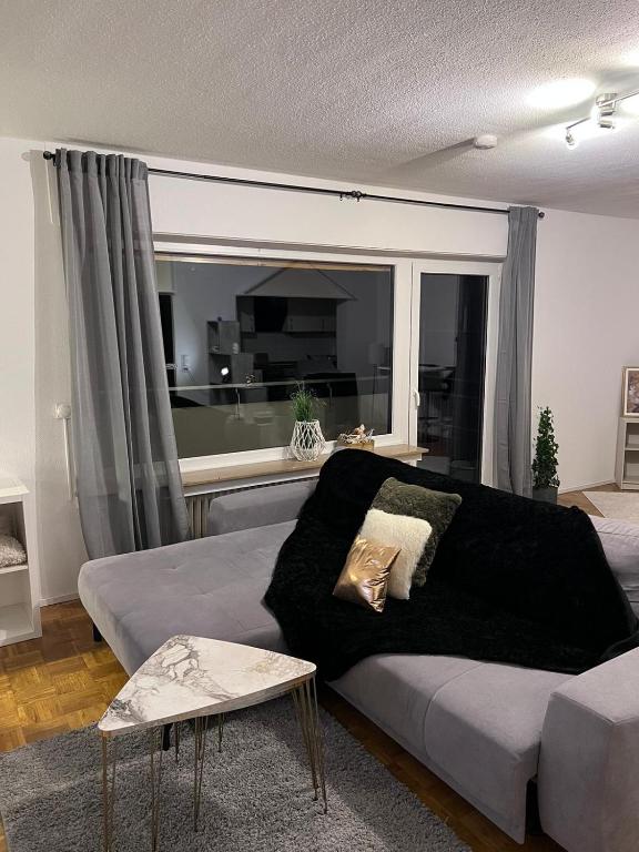 ein Wohnzimmer mit einem Sofa und einem großen Fenster in der Unterkunft Zentral gelegenes Apartment - DSL, Küche, Balkon, Parkplatz in Lüdenscheid