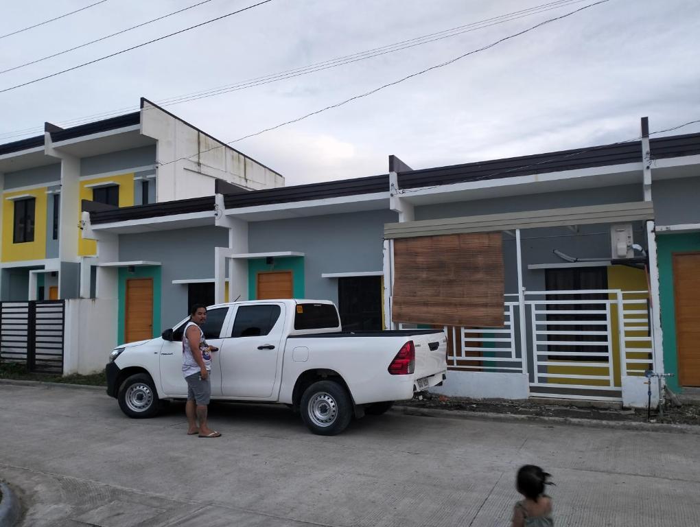 a man standing next to a white truck parked in front of a house at Catalena Transient House Bayugan City in Bayugan City