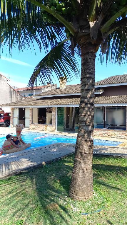 una persona tumbada en una piscina junto a una palmera en Casa de Praia com Piscina em Peruíbe, en Peruíbe