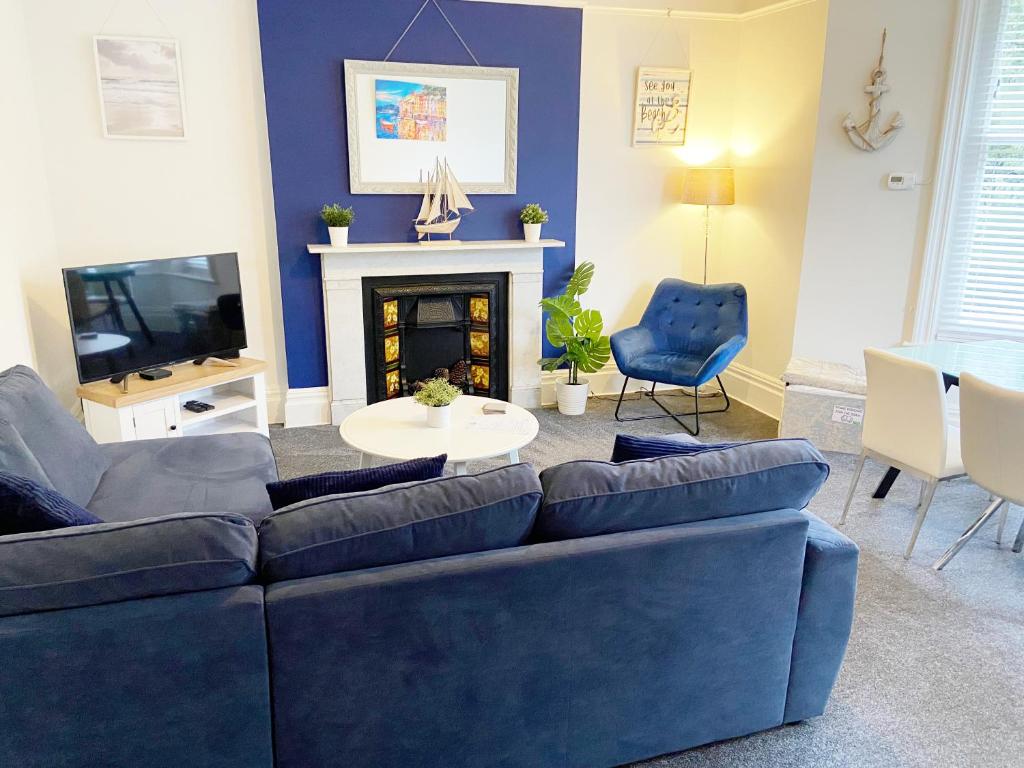 a living room with a blue couch and a fireplace at Sail Away. 1-Bed apartment close to the beach in Bournemouth
