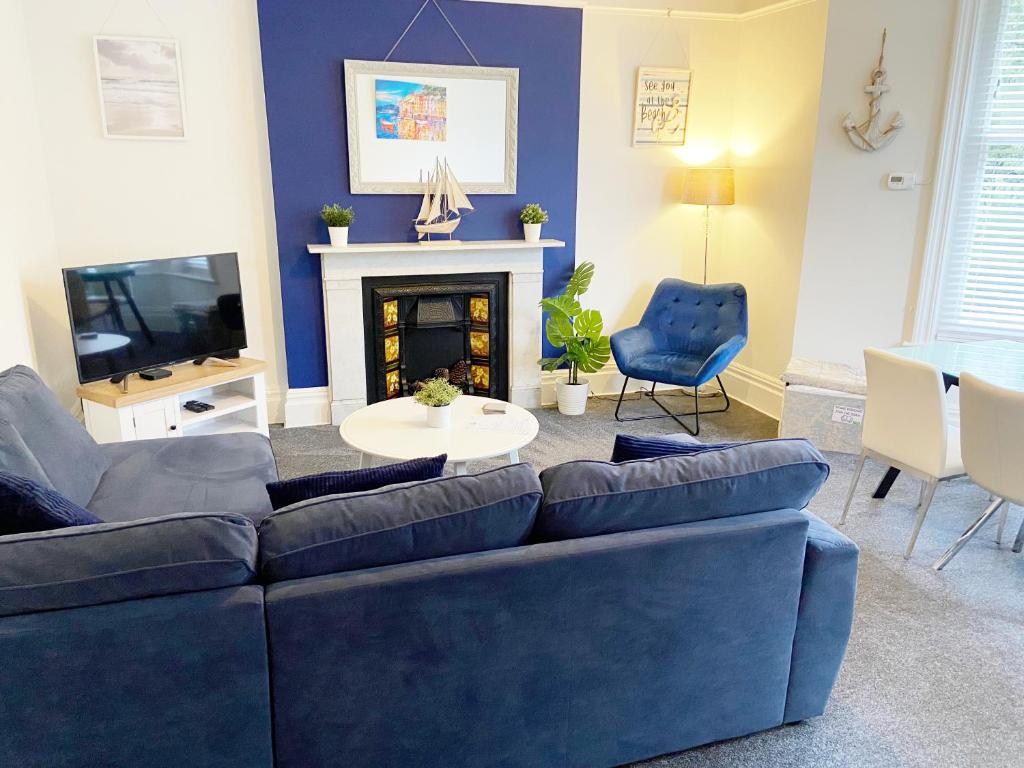 a living room with a blue couch and a fireplace at April Lodge Sail Away- 1Bed apartment close to the beach-Parking-Couples-Professionals-Contractors in Bournemouth