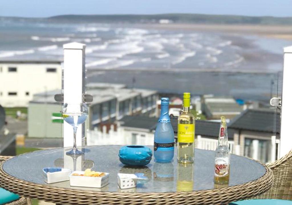 a table with bottles of alcohol on top of a balcony at Braddicks Holidays - Sea View Apartments & Caravans in Westward Ho