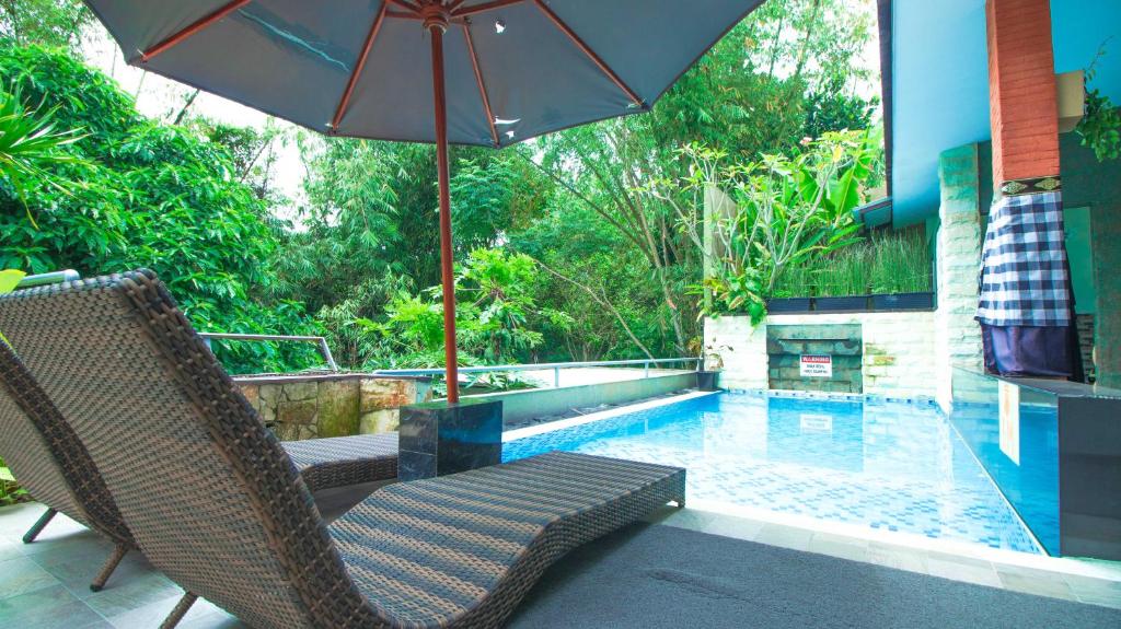 una piscina con 2 sillas y una sombrilla en Villa Dewata with Chill Spot Private Pool and Karaoke, en Batu