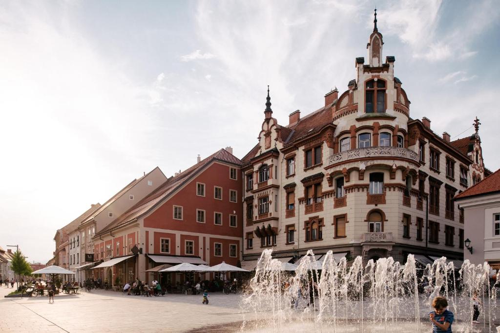 a large building with a fountain in front of it at Hotel Maribor, City apartments in Maribor