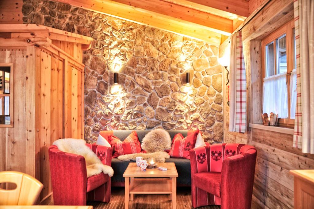 - un salon avec un canapé, des chaises et un mur en pierre dans l'établissement Luxury Chalets Wiesenruh, à Bichlbach