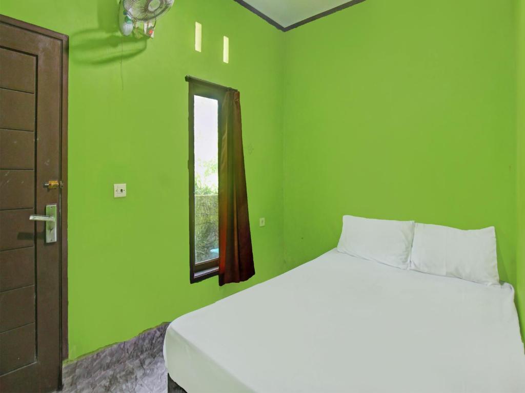a green bedroom with a bed and a window at OYO 92149 Ashooy Homestay in Lombok