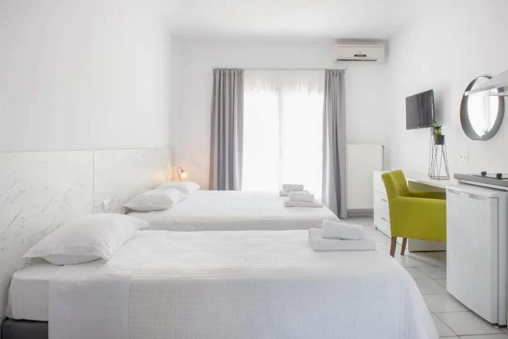 a white room with two beds and a yellow chair at Hotel Papanikolaou in Ierissos