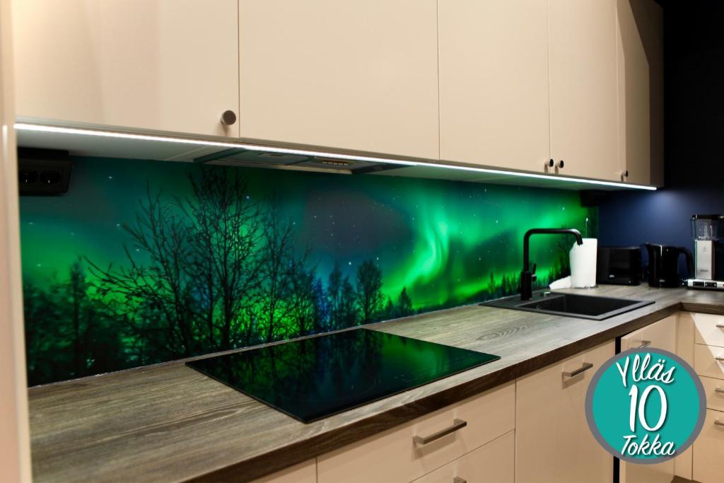 eine Küche mit einer grünen Wand mit Nordlichtern in der Unterkunft Yllästokka 10 in Ylläsjärvi