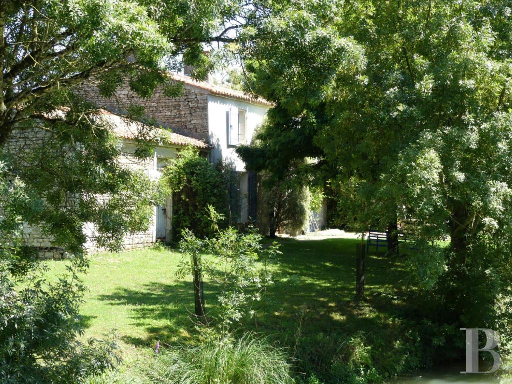 una casa con un patio con árboles delante de ella en ONEIRO NISOS, en Maillé