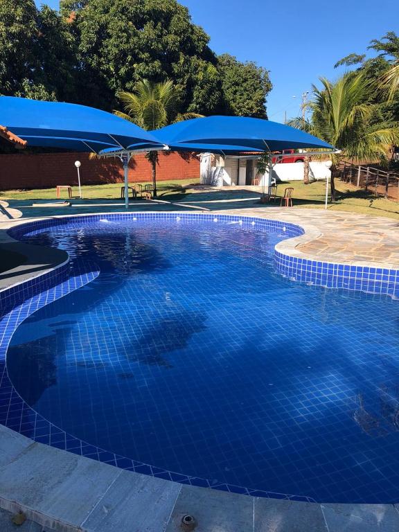 a large blue swimming pool with a blue umbrella at Hotel Fazenda Pousada da Serra in Goianésia