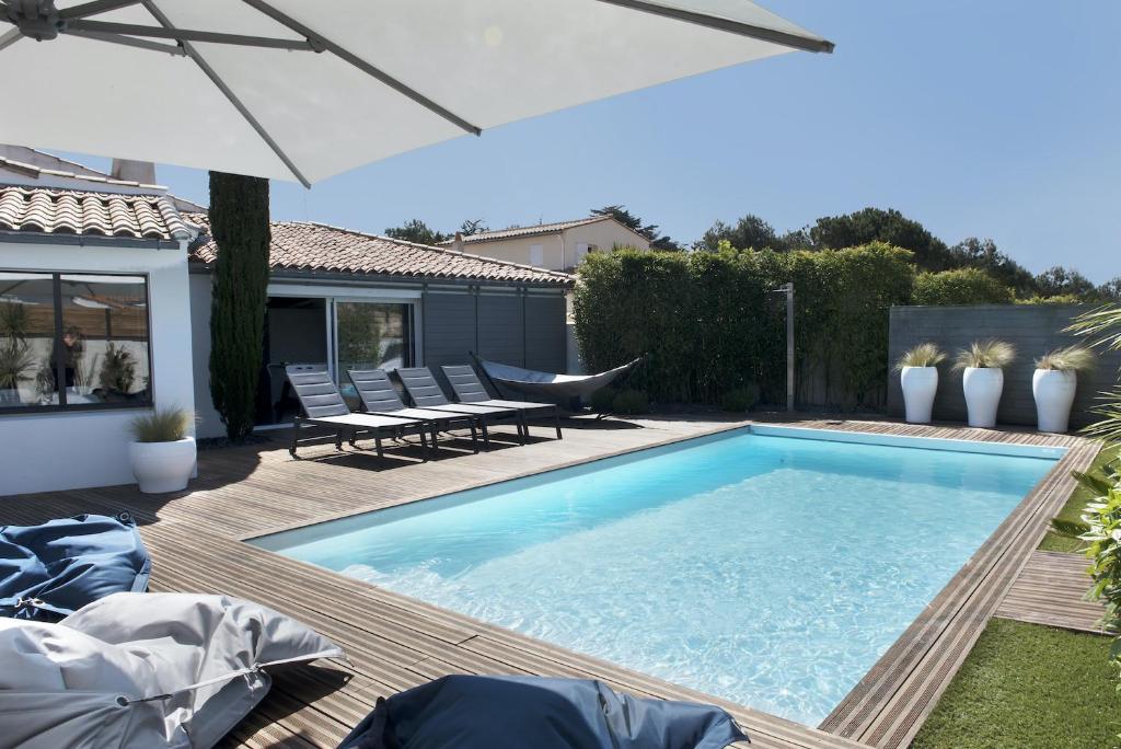 a swimming pool with two chairs and an umbrella at Villa Piscine tout confort in La Flotte