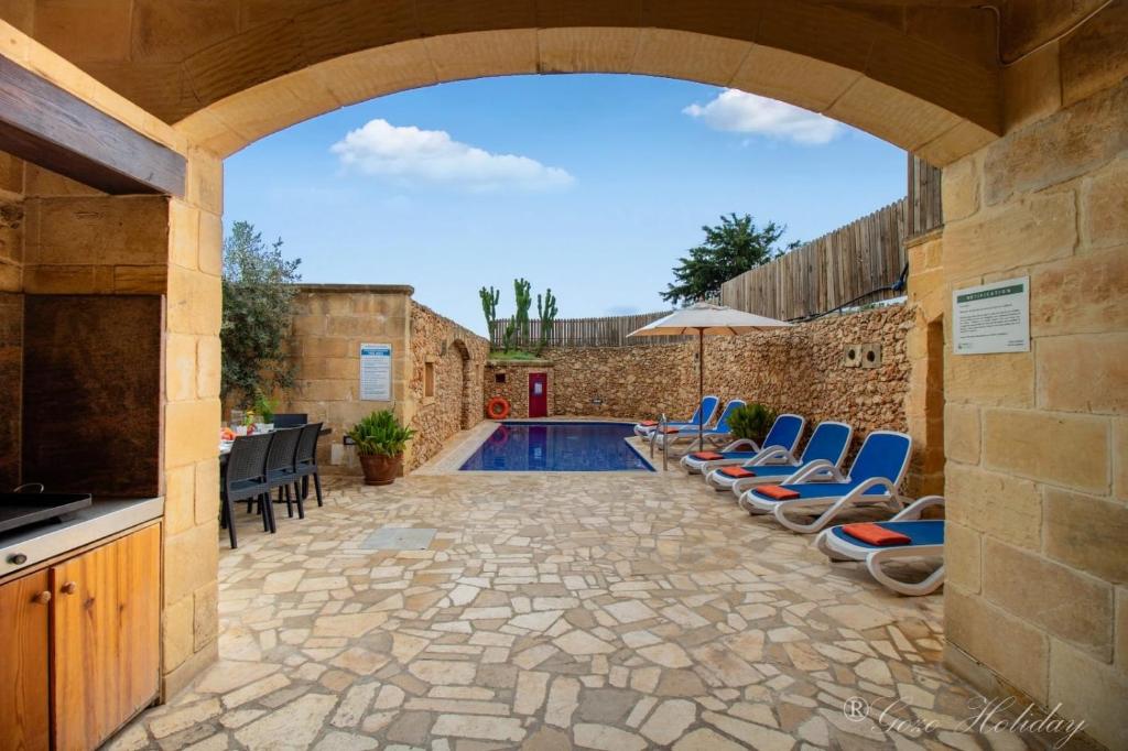 eine Terrasse mit Stühlen und einem Pool in der Unterkunft Tan-Nanna Holiday Home in Xagħra