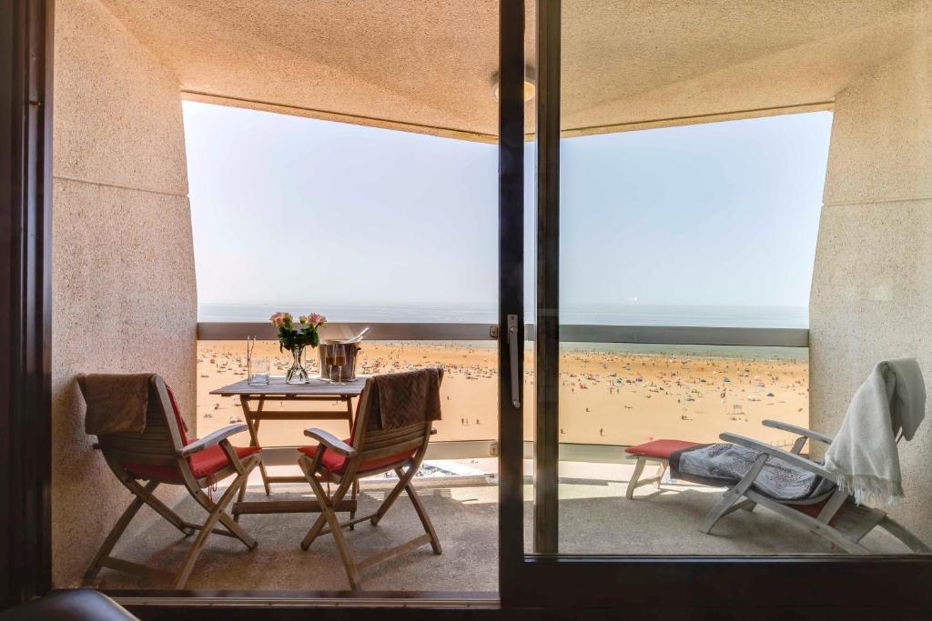 een eetkamer met een tafel en stoelen en een strand bij Luxury Suite with Seaview in Oostende