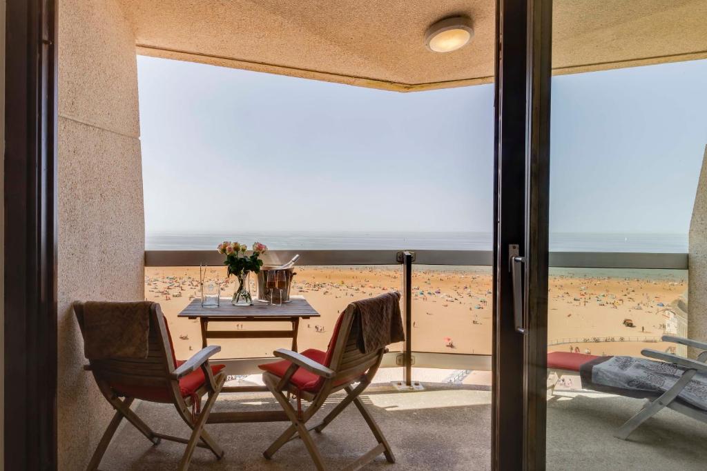 a room with a table and chairs and a beach at Luxury Suite with Seaview in Ostend