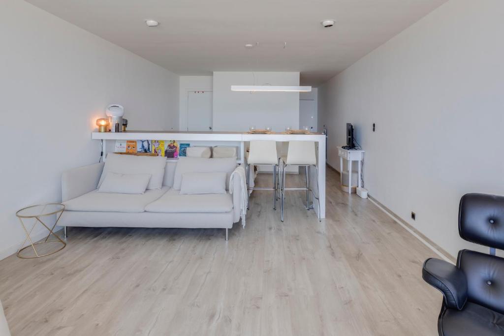 a living room with a white couch and a kitchen at Luxury Suite with Seaview in Ostend